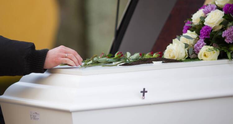 A closeup shot of a person hand on a casket with a blurred background